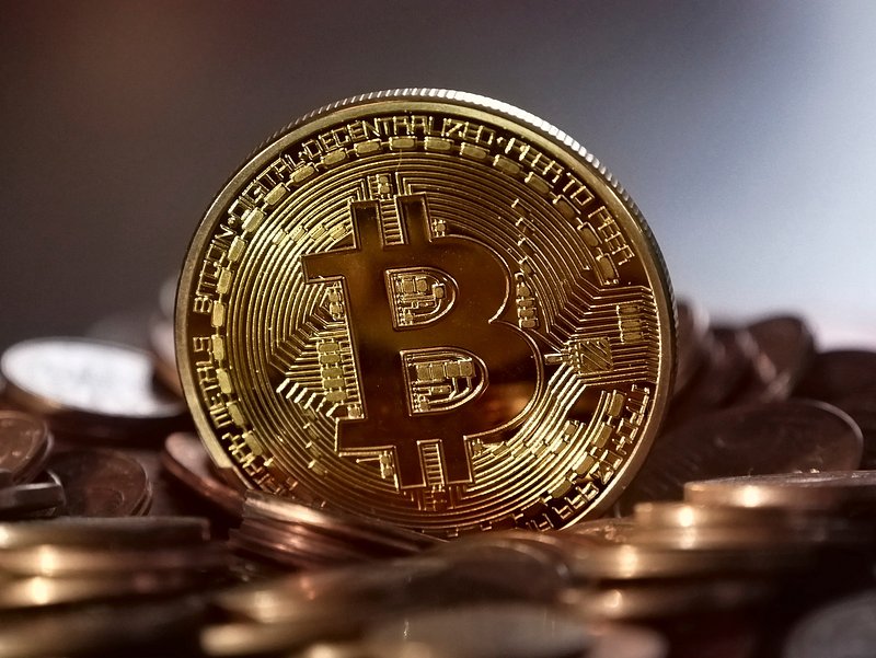 A close-up of a Bitcoin placed on a pile of coins, highlighting cryptocurrency for trading.